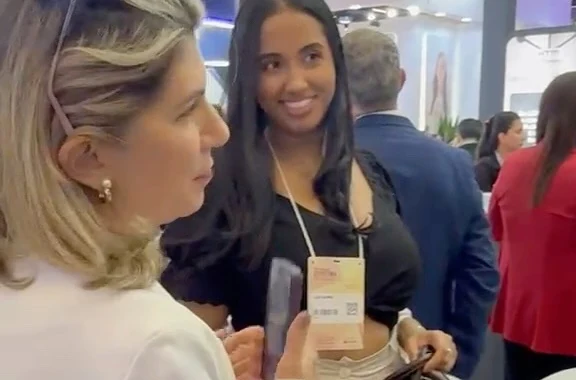 Lucília de jaleco em congresso de estética, conversando com colega entre equipamentos