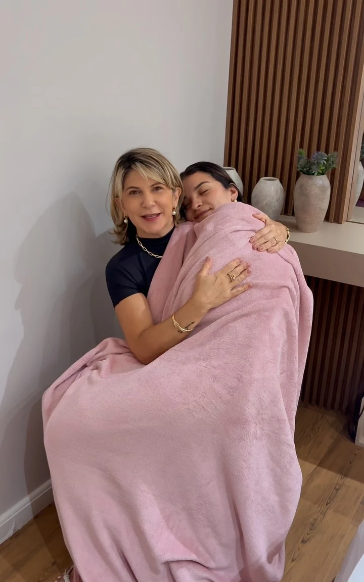 Cliente relaxando na maca envolvida em toalha rosa